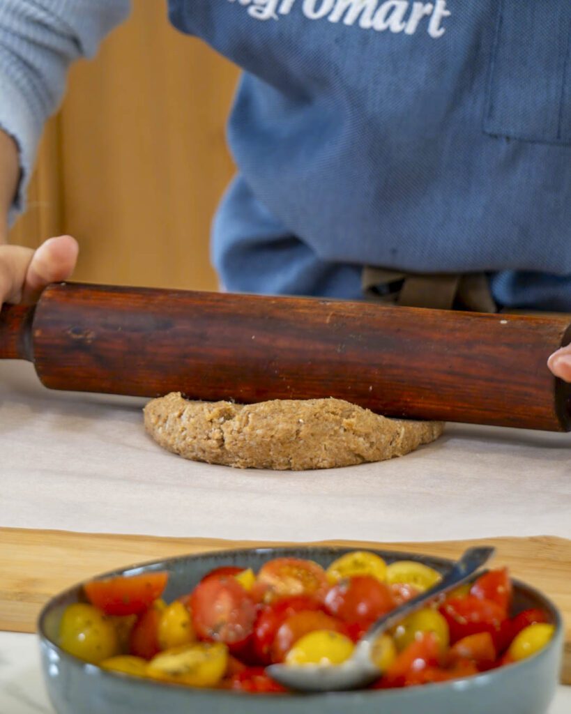 Damunt un paper de forn, estira la pasta recepta coca de tomàtiga xerri Agromart